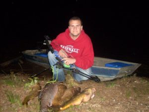 mon posing with many fish caught while carp fishing with a bow. 