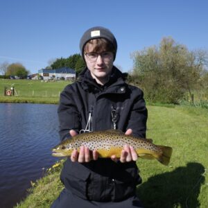  A fisherman holds up a small brown trout. 