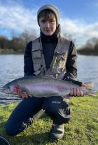 A fisherman holds out a large rainbow trout. 
