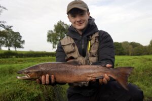 A fisherman holds out an Atlantic Salmon.