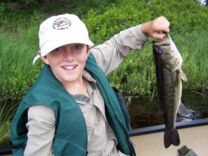 A young child proudly holds up his bass. 