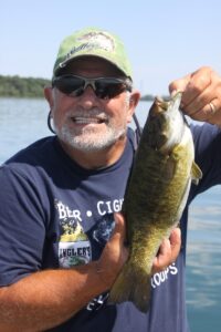 A man holds up a bass while grinning. 