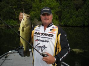 Professional angler holding a largemouth bass while spinning from a boat. 