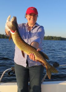 A happy fisherman holds up a northern pike.