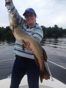 A happy lady holds her northern pike with boga grips.