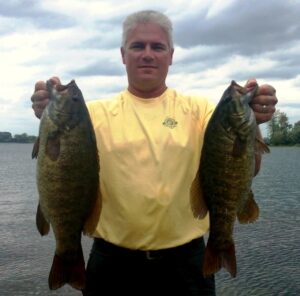 Proud angler posing with two bass, one in each hand.