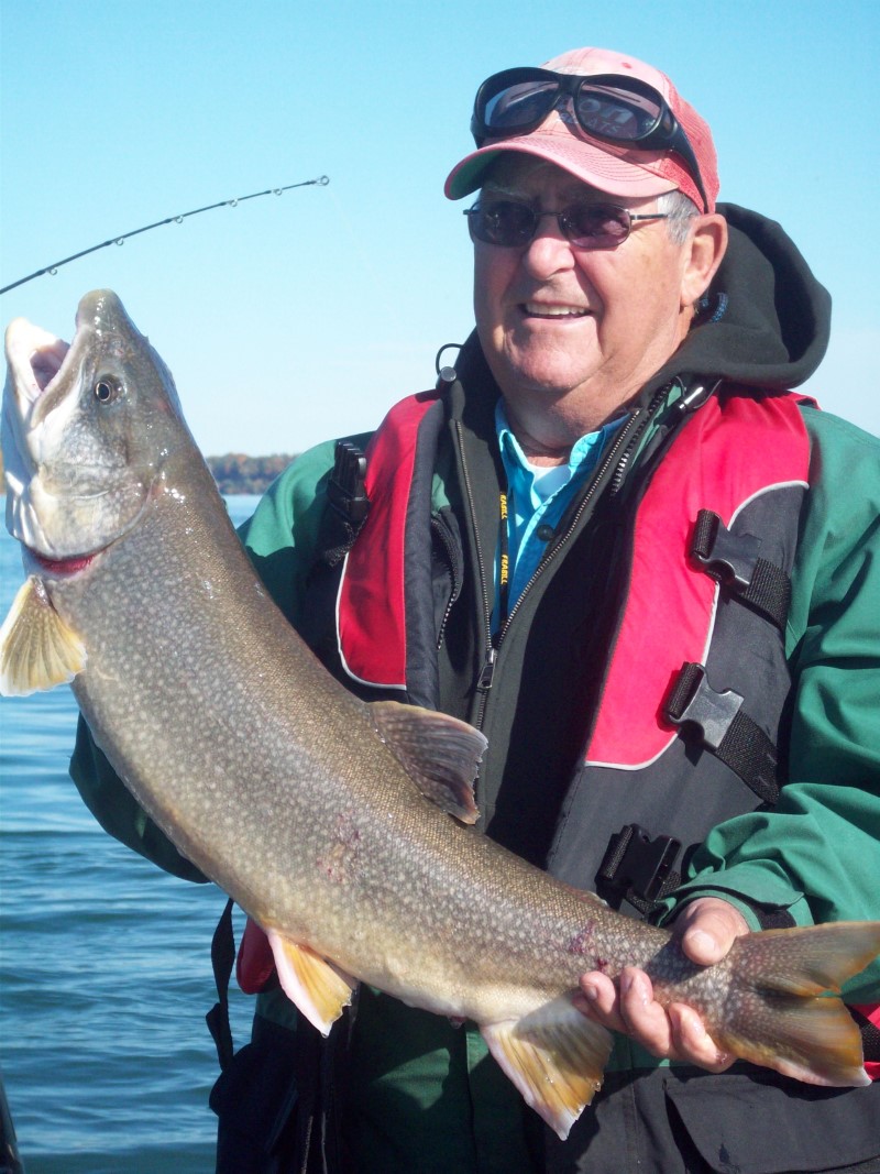 A fisherman holds out an average-sized lake trout he just caught. 