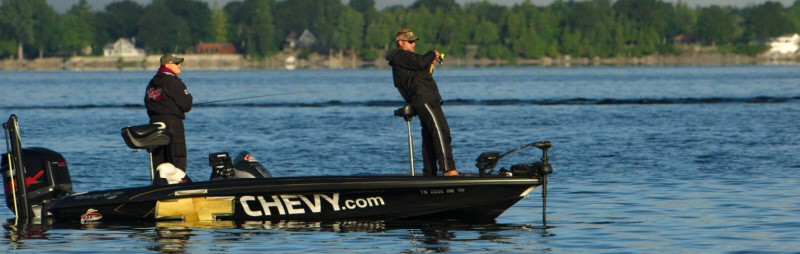 Two fishermen catching bass from their boat at a lake champlain bass fishing tournament. 