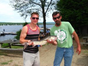 A father and his son hold a walleye they caught while fishing. 