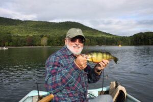An older angler reels in his catch while fishing on a boat. 