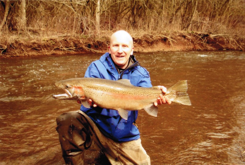  A large steelhead is held by a happy angler.