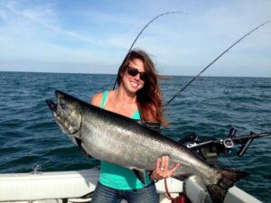 An angler holds up a large king salmon while boat fishing.