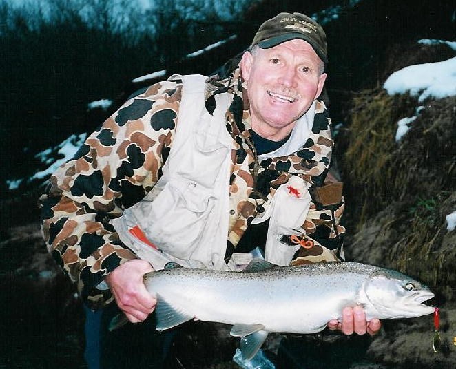 A fisherman holds a steelhead he caught with the spinner still in its mouth. 