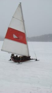 An angler sits on an ice boat while out fishing on a frozen lake. 