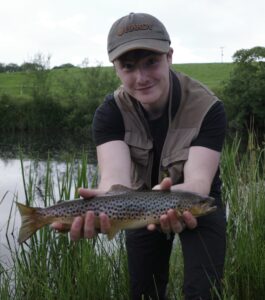 A fisherman showcases a brown trout. 