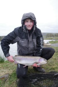 A fisherman holds out a rainbow trout. 