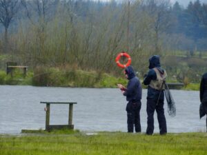 A fisherman plays a large rainbow trout on a fishing rod. 