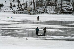 A group of ice fisherman stand out on frozen lake.