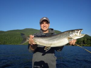 A young angler proudly holds up an impressive lake trout. 