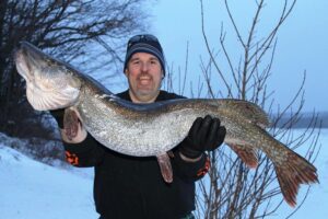 A happy angler holds up a big northern pike. 