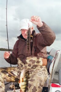 Fisherman holds up two perch on one rig. 