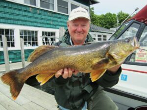 A trophy-sized walleye held up on a fishing dock.