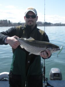 A fisherman holds up a brown trout caught while drift fishing. 
