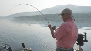 An angler hooks into a fish while on a boat. 