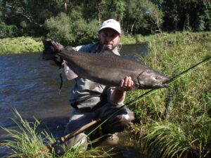 A fisherman holds up a large chinook salmon he caught from the shore. 